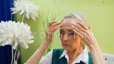 老年妇女正在做抗衰老的面部按摩，以对抗皱纹。